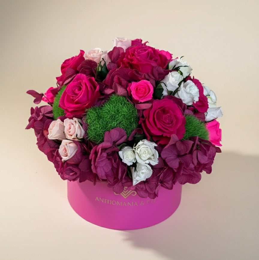 side view of hydrangeas and roses arranged in a dome inside the hot pink small hat box