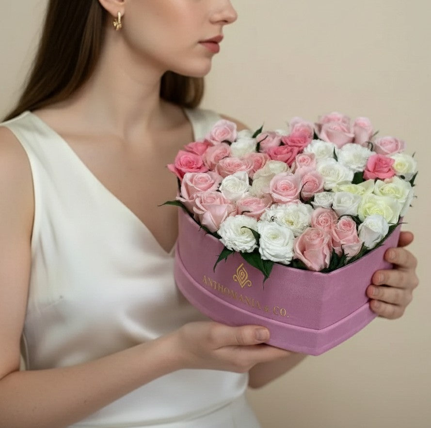 model holding roses in a large pink heart shape box with white and pink blooms