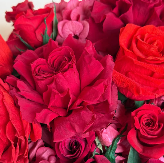 close up of red roses mixed with red hydrangeas arranged tightly in the black hat box