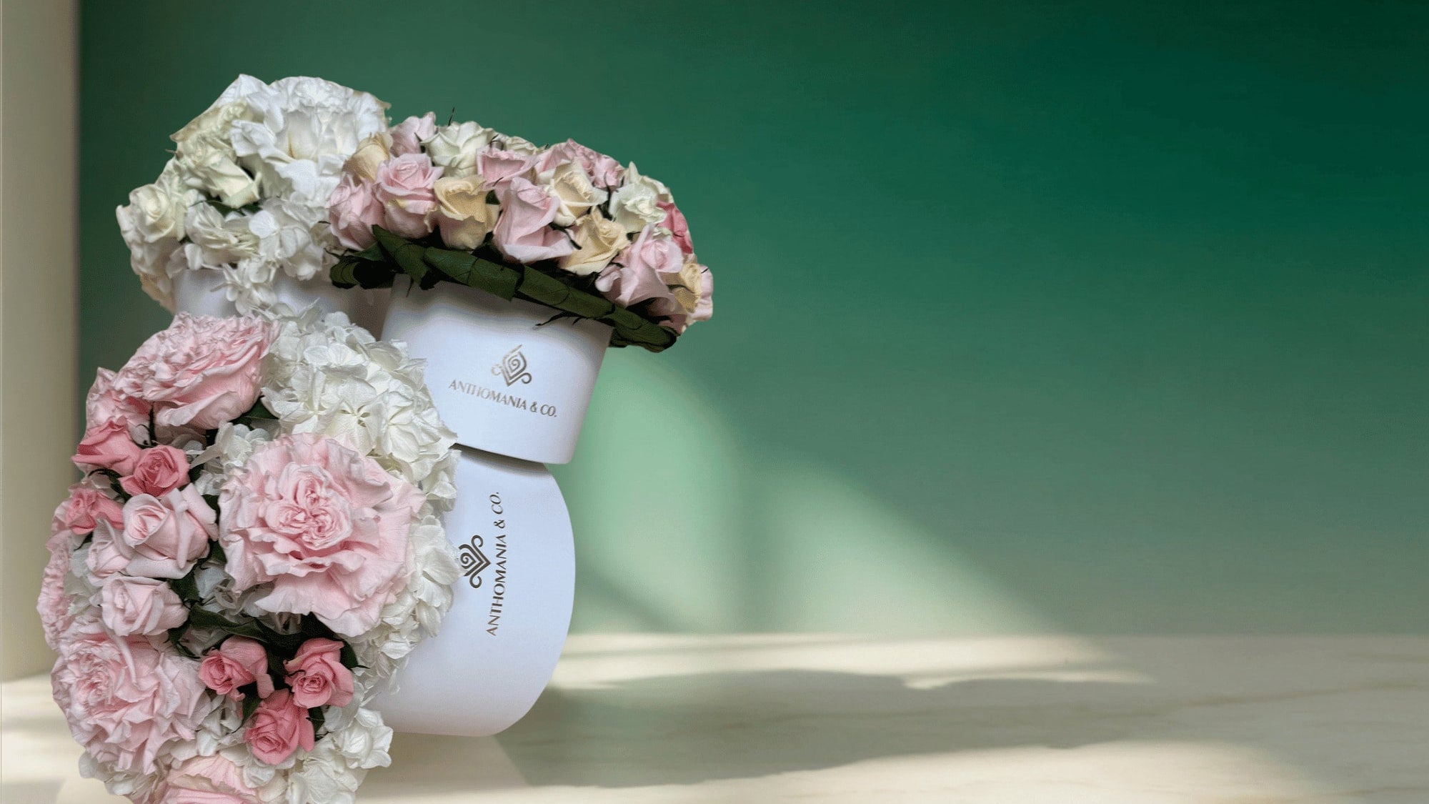 Two white containers with floral arrangements on top against a green background