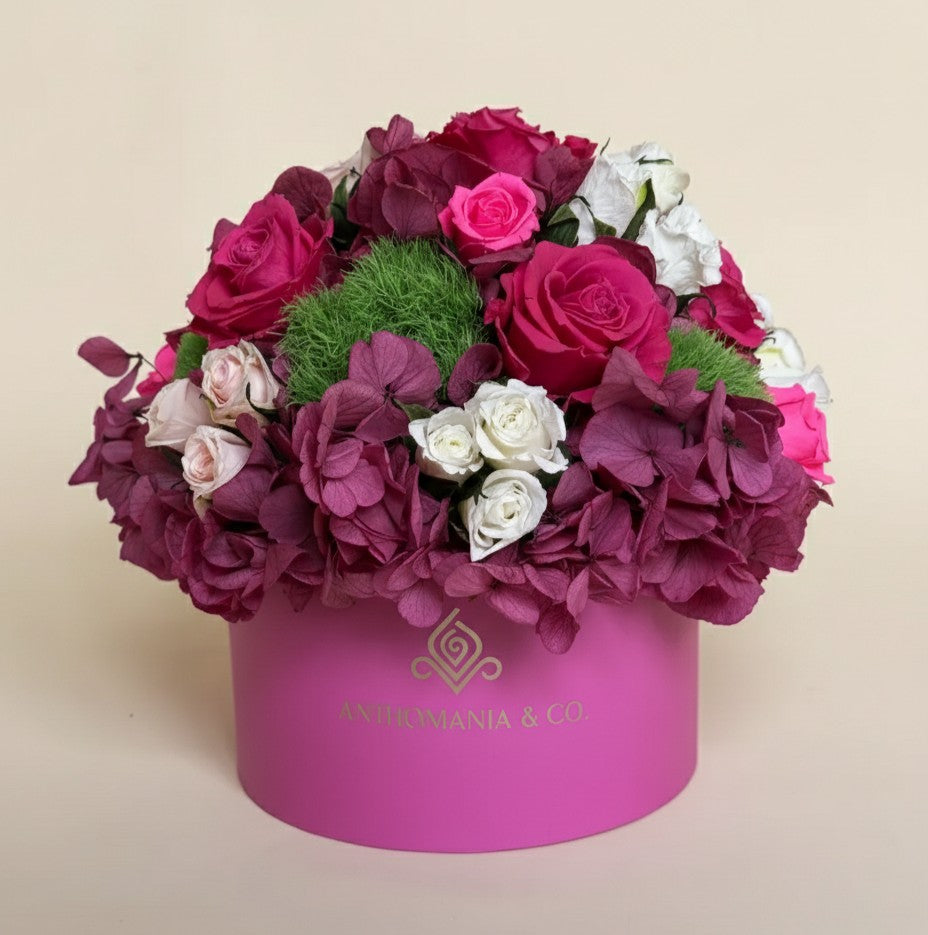 front view of hydrangeas and roses arranged in a dome inside the hot pink small hat box