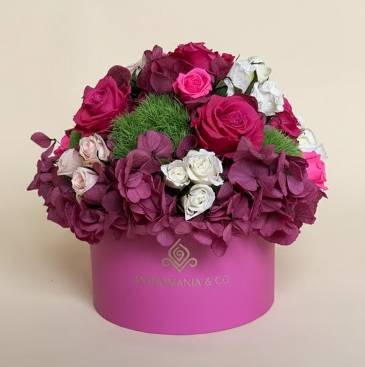 front view of hydrangeas and roses arranged in a dome inside the hot pink small hat box