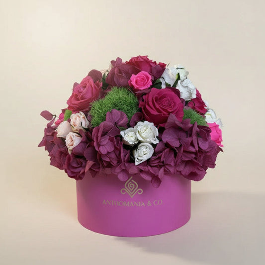 front view of hydrangeas and roses arranged in a dome inside the hot pink small hat box