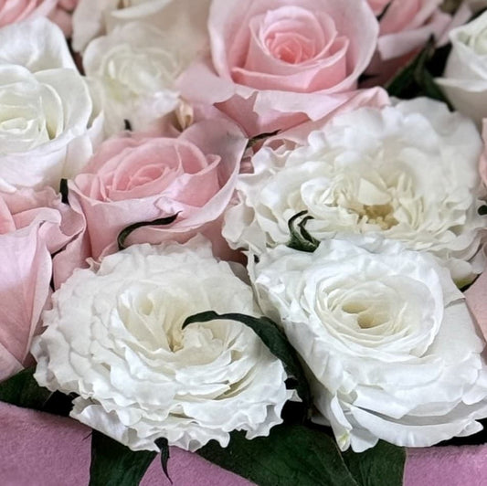 close up of white and pink roses placed tightly inside the pink heart shape box