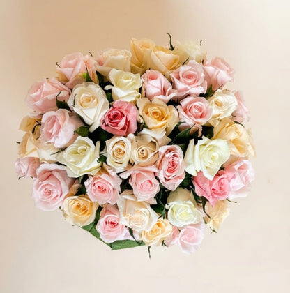top view of mini roses displaying pink and white petals filling the small white hat box