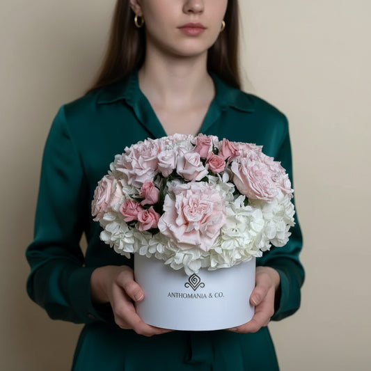 model holding hydrangeas and roses in a white large hat box with pink and white